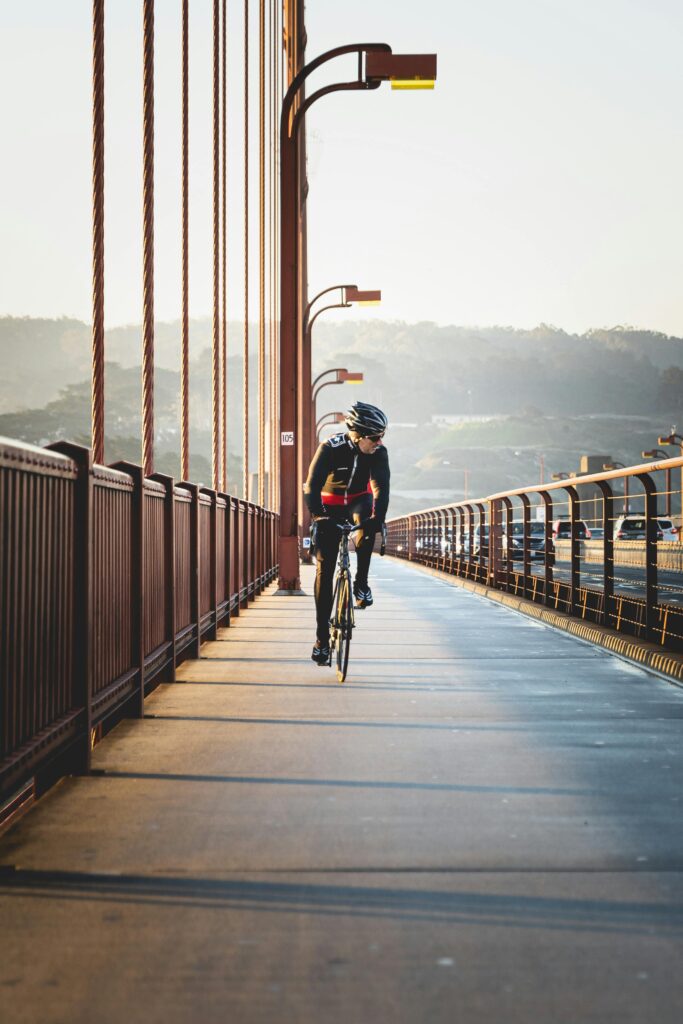 A cyclist rides across the iconic Golden Gate Bridge in San Francisco on a sunny day.